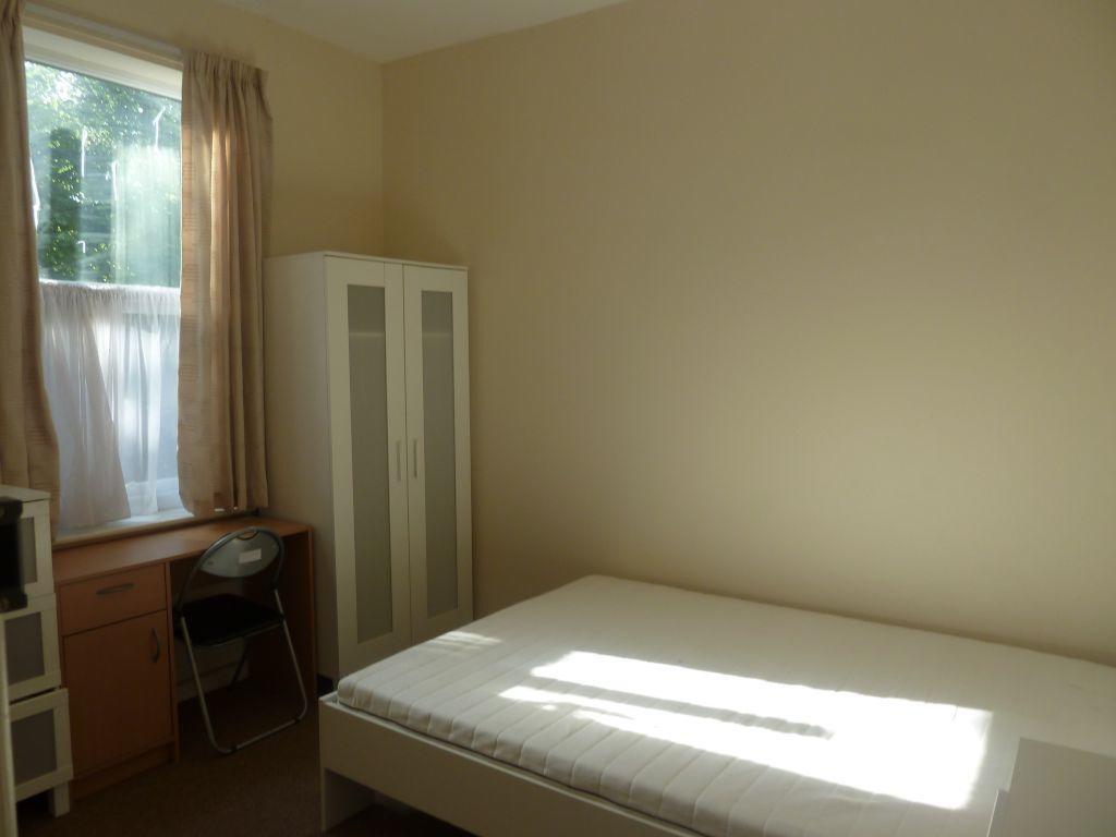 Bright single bedroom featuring a large window ...
