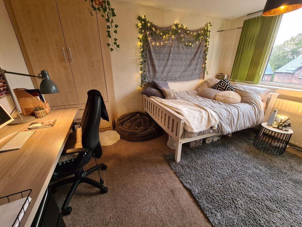 A cozy single bedroom with a neatly made bed, a...