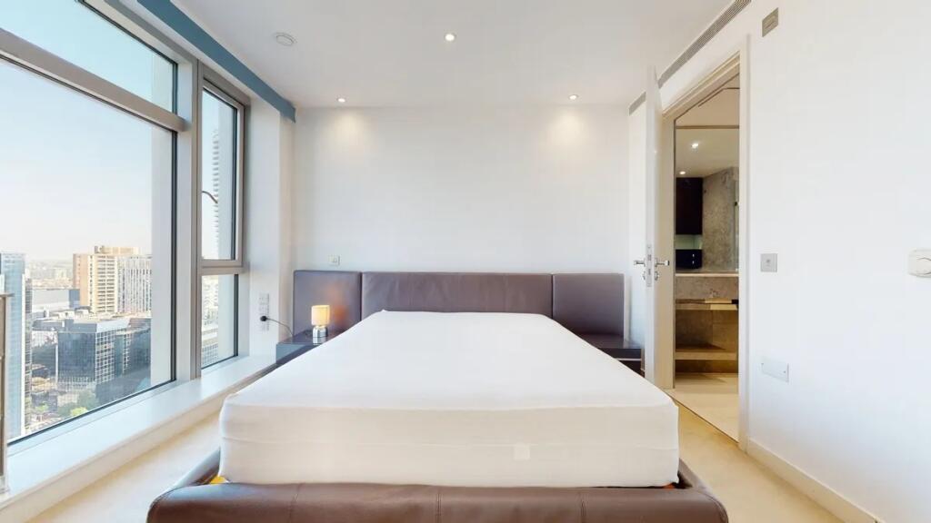 Bright and modern master bedroom featuring a la...