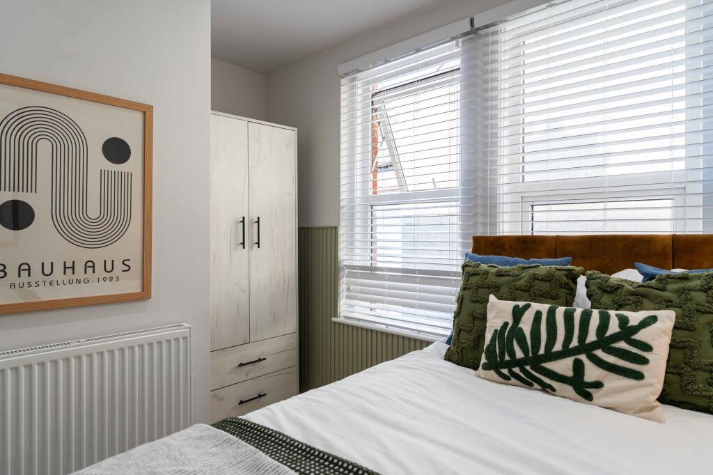 A cozy, well-lit bedroom featuring a comfortabl...