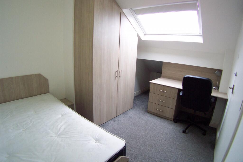 A compact single bedroom featuring a bed, a lar...