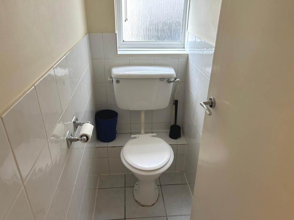 Compact and tidy WC with white tiled walls, a w...