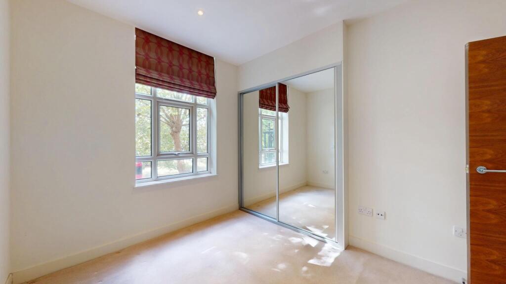 A bright double bedroom featuring a large windo...