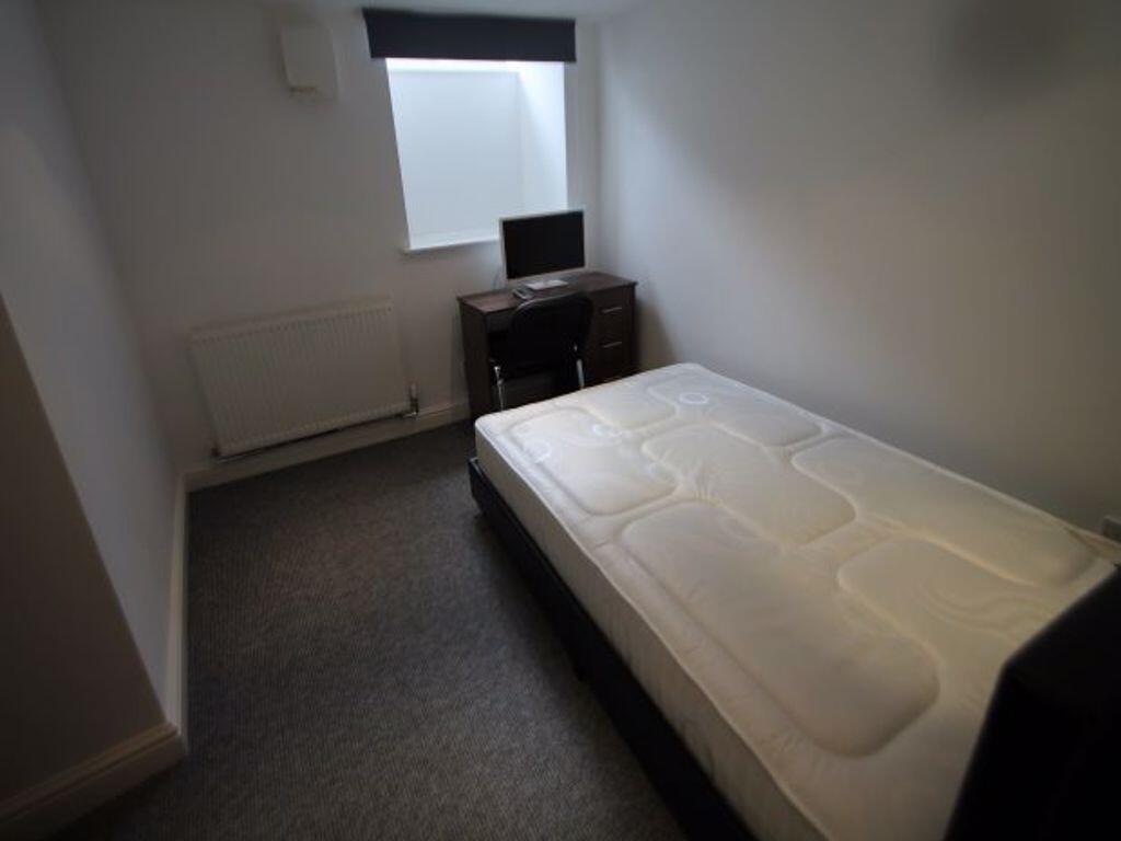 A compact single bedroom featuring a neatly mad...