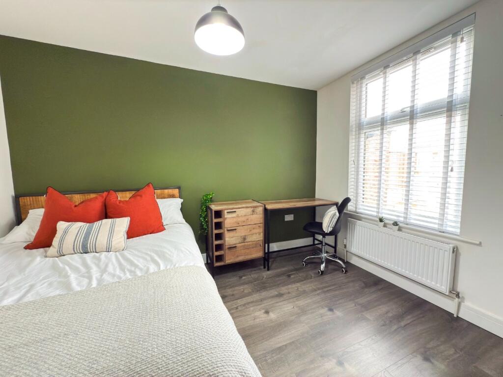 A bright and welcoming bedroom featuring a comf...