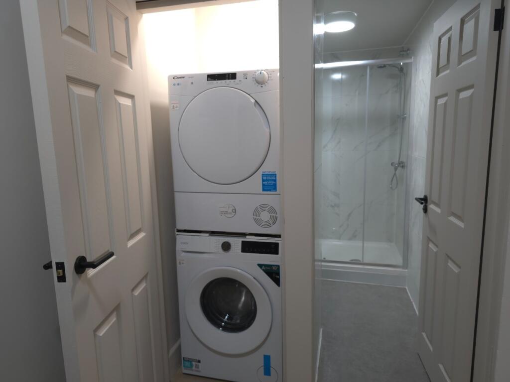 Bright, tidy hallway with integrated stacked wa...