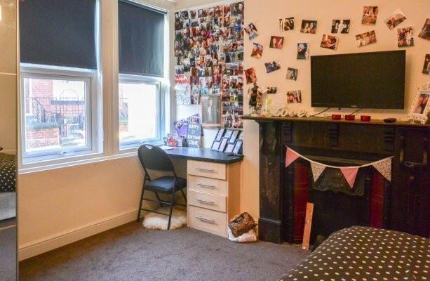 A cozy bedroom with two large windows providing...