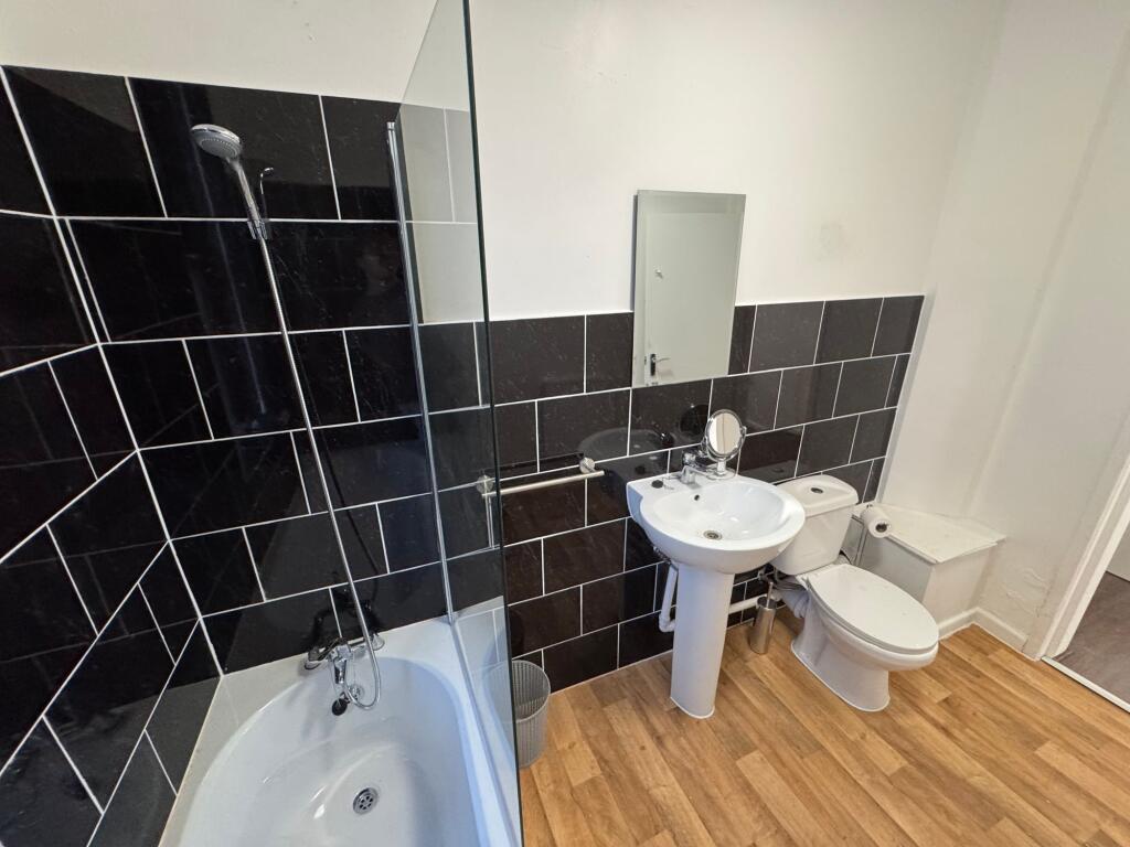 A modern bathroom suite featuring a white batht...