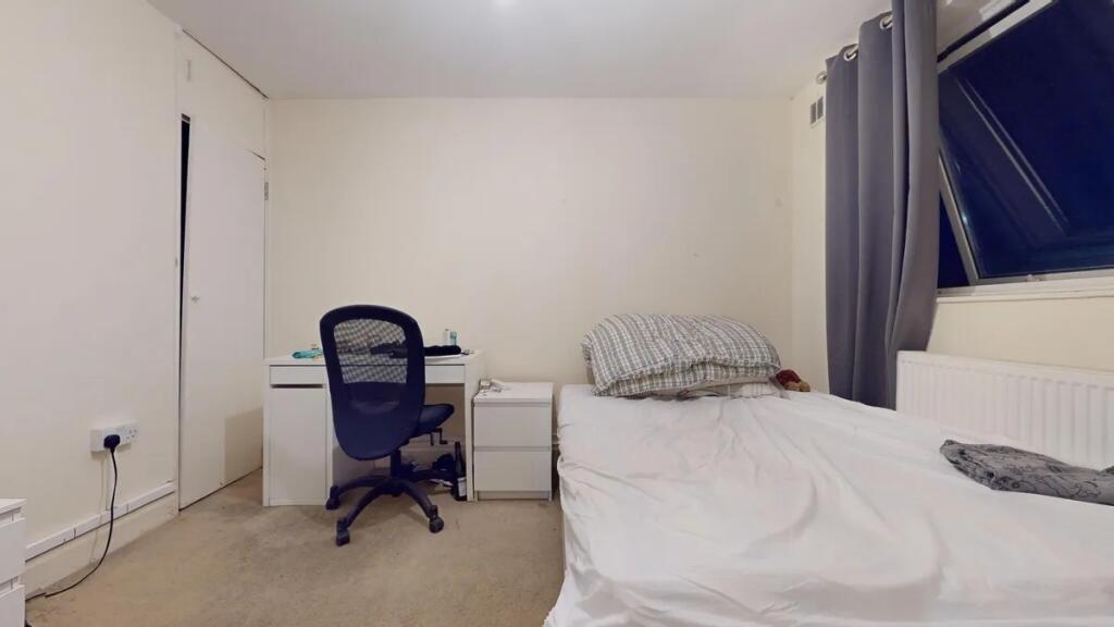 A cozy single bedroom featuring a neat study de...