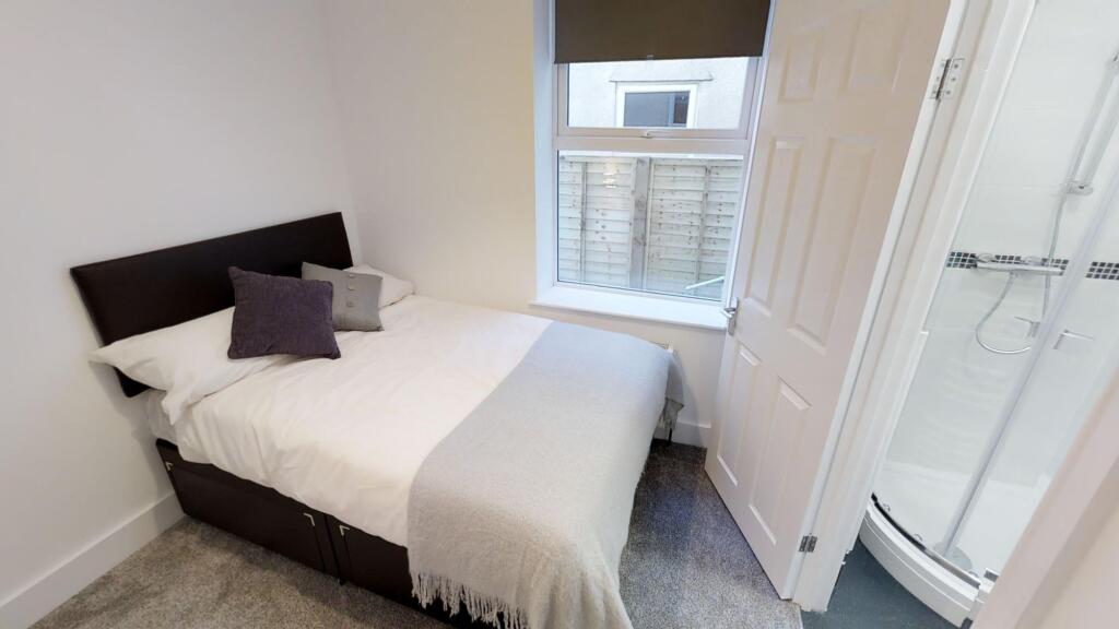 A neat and tidy double bedroom featuring a comf...