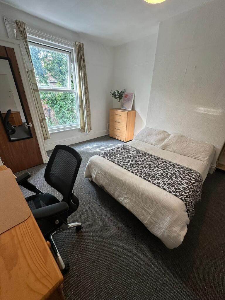A bright and tidy bedroom featuring a comfortab...