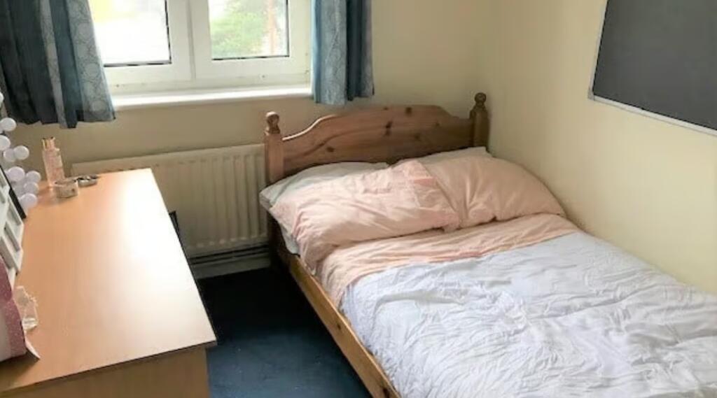 Cozy single bedroom featuring a wooden bed fram...