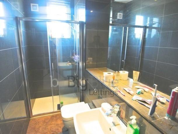 A modern bathroom suite featuring a glass-enclo...