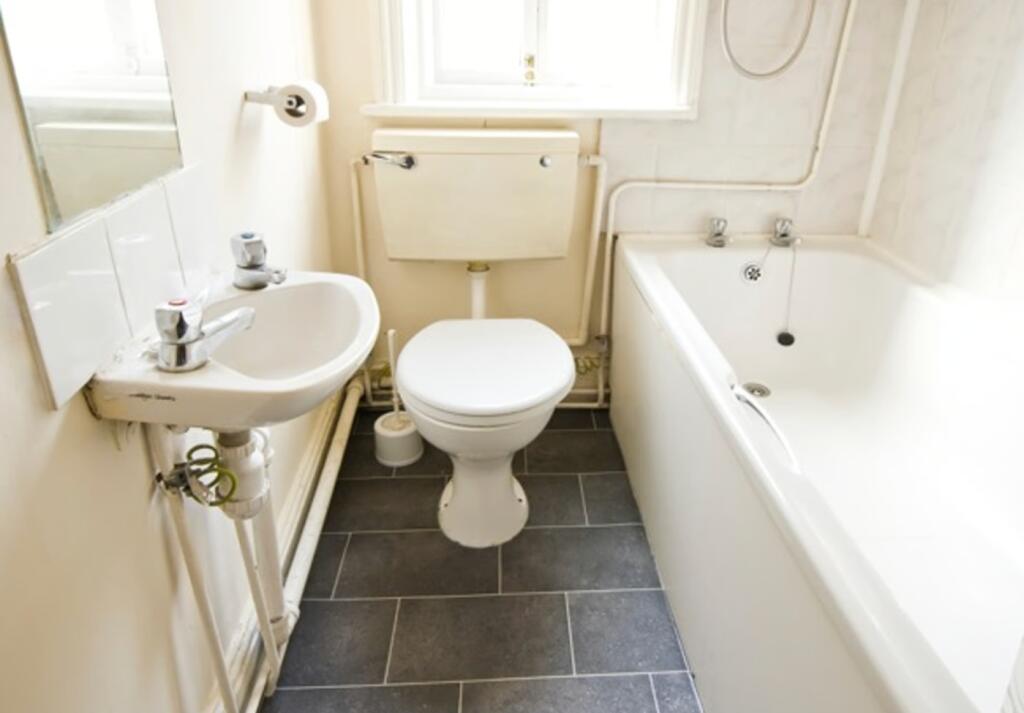 A tidy and bright bathroom featuring a bathtub ...