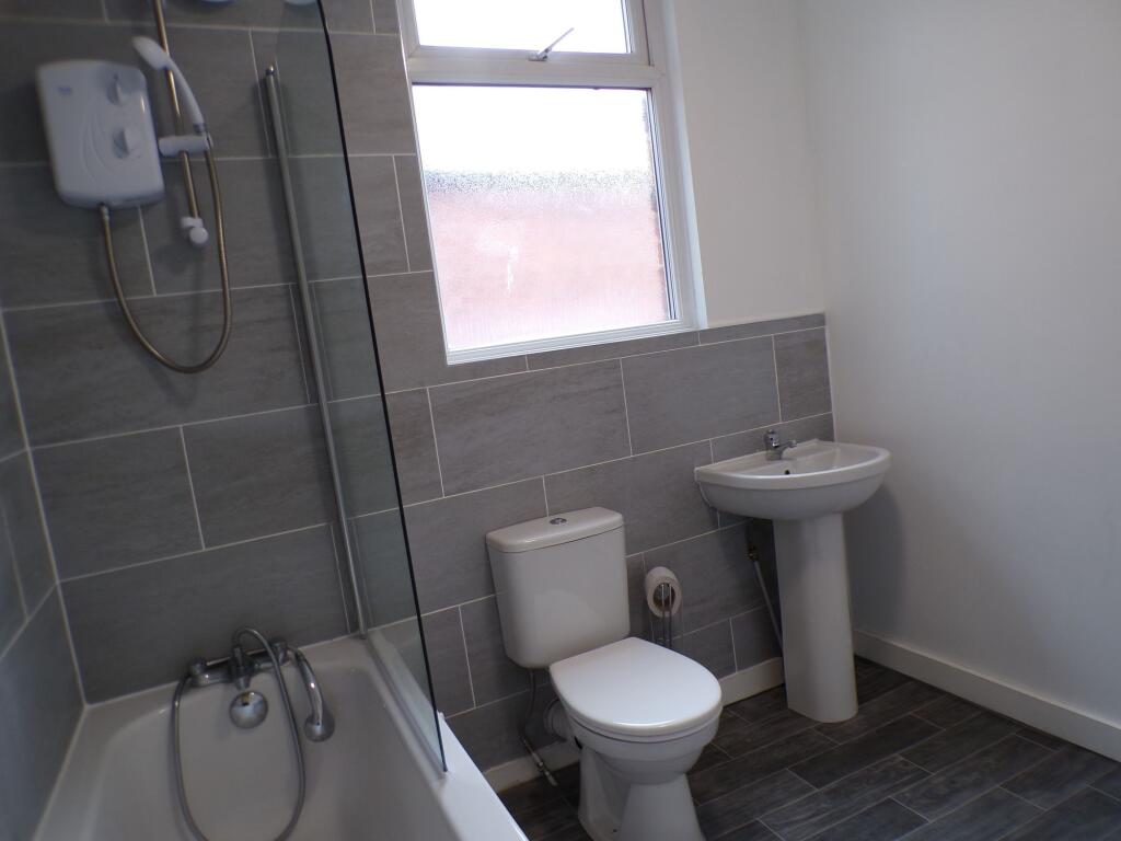 A clean, modern bathroom featuring a bathtub wi...