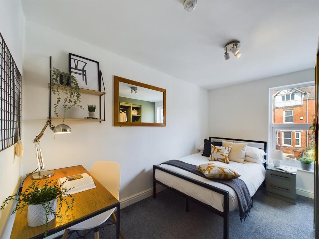 A bright and tidy small bedroom featuring a com...