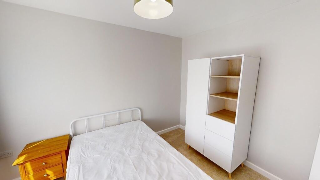A bright, simple bedroom featuring a single bed...