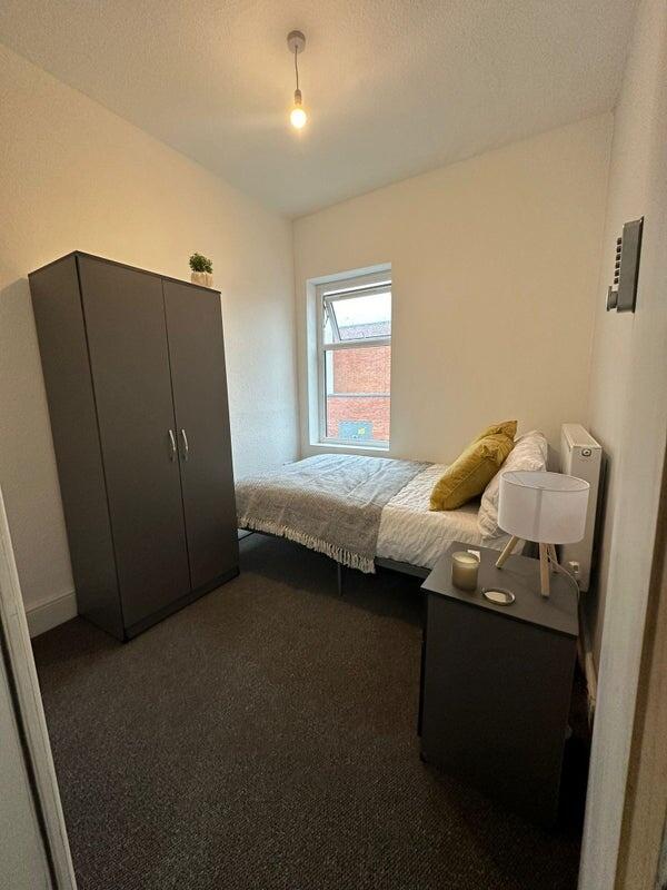 A cozy and neatly arranged single bedroom featu...