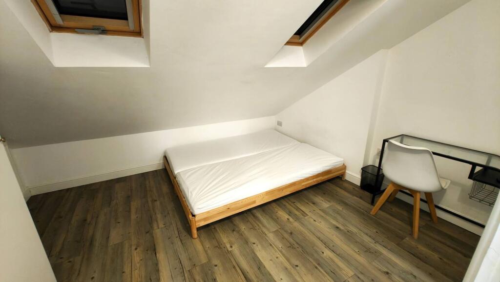A cozy student's bedroom featuring a single bed...