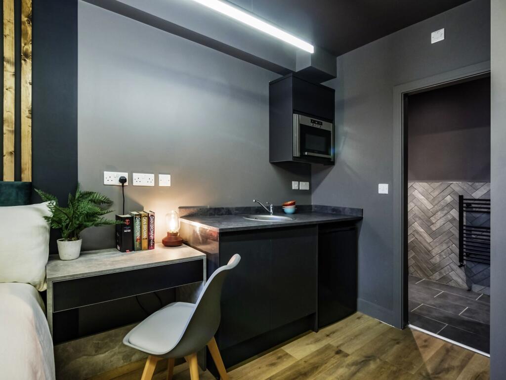 Modern compact kitchen area featuring sleek bla...