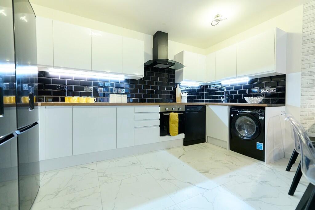 A sleek, modern kitchen featuring high-gloss wh...
