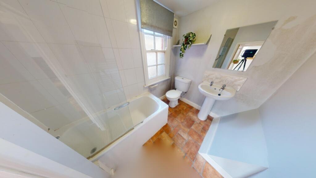 A bright and tidy bathroom featuring a bath and...