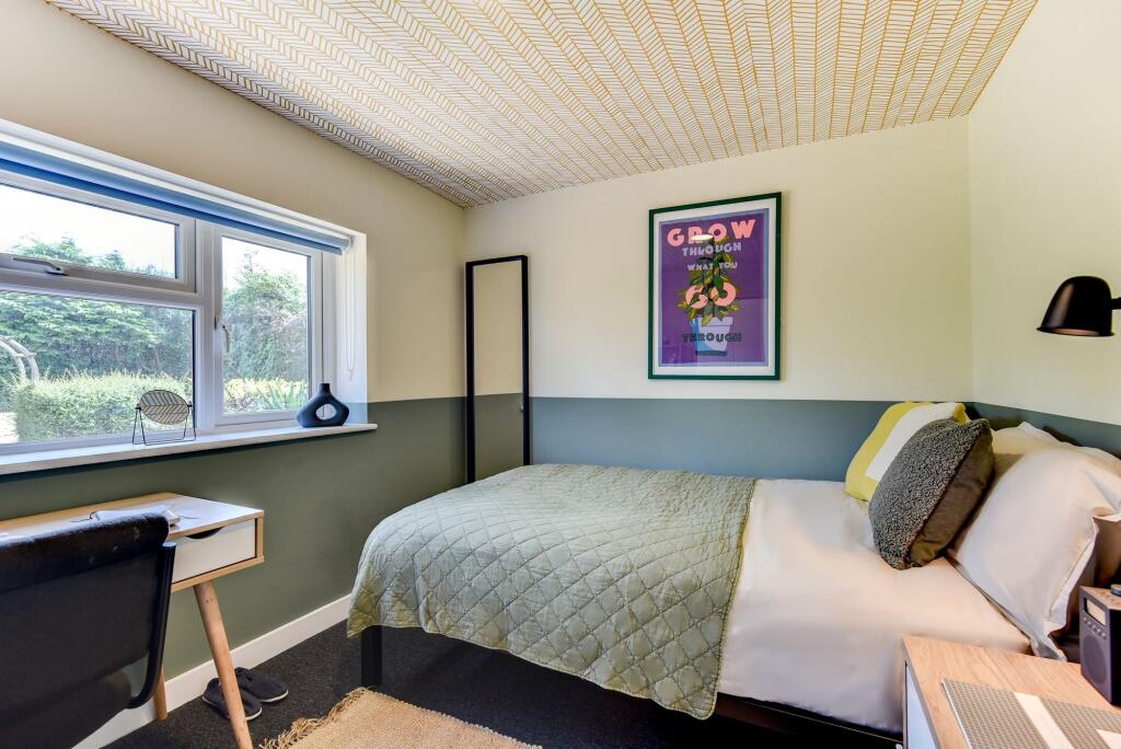 A cozy and well-lit single bedroom featuring a ...