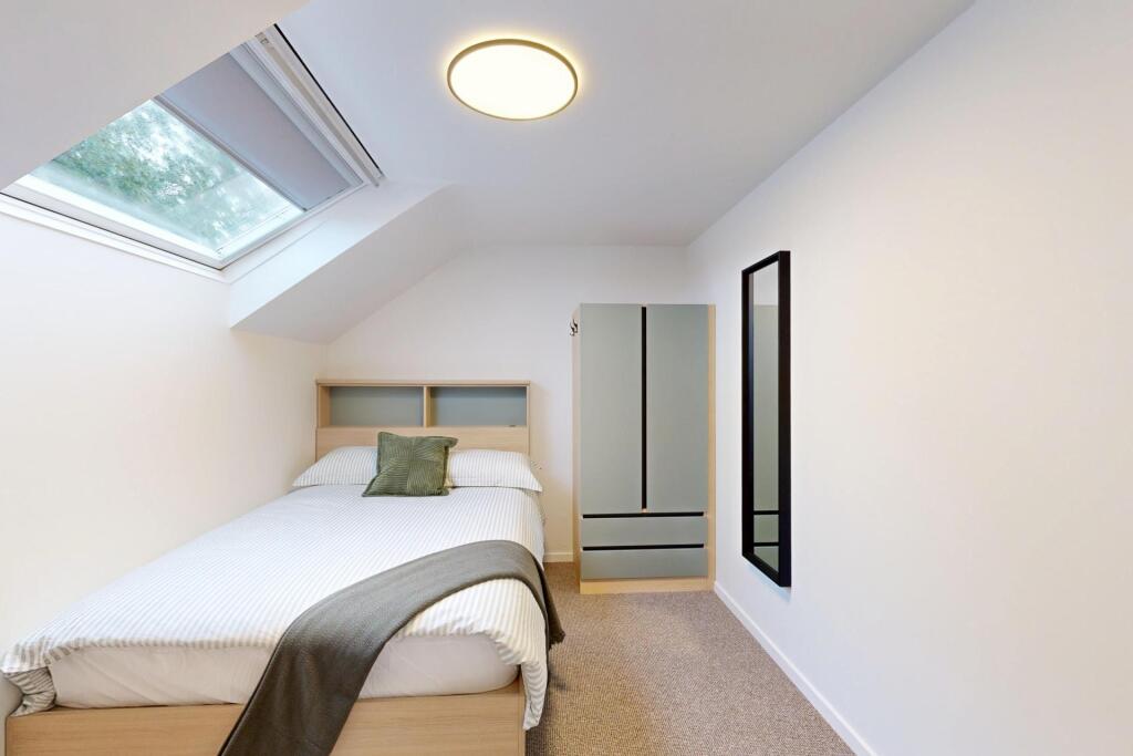 Bright, neatly furnished attic bedroom with a c...