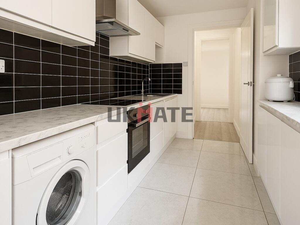 Modern kitchen with sleek white cabinetry, blac...