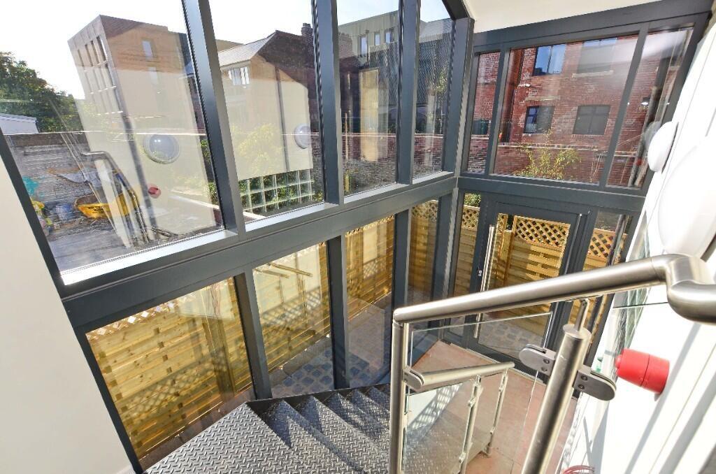 Bright and modern staircase area featuring larg...