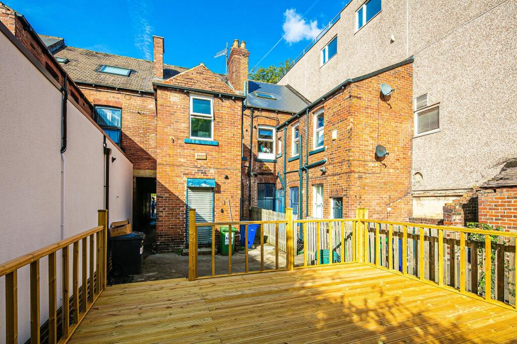 Sunny raised wooden deck overlooking a brick-bu...
