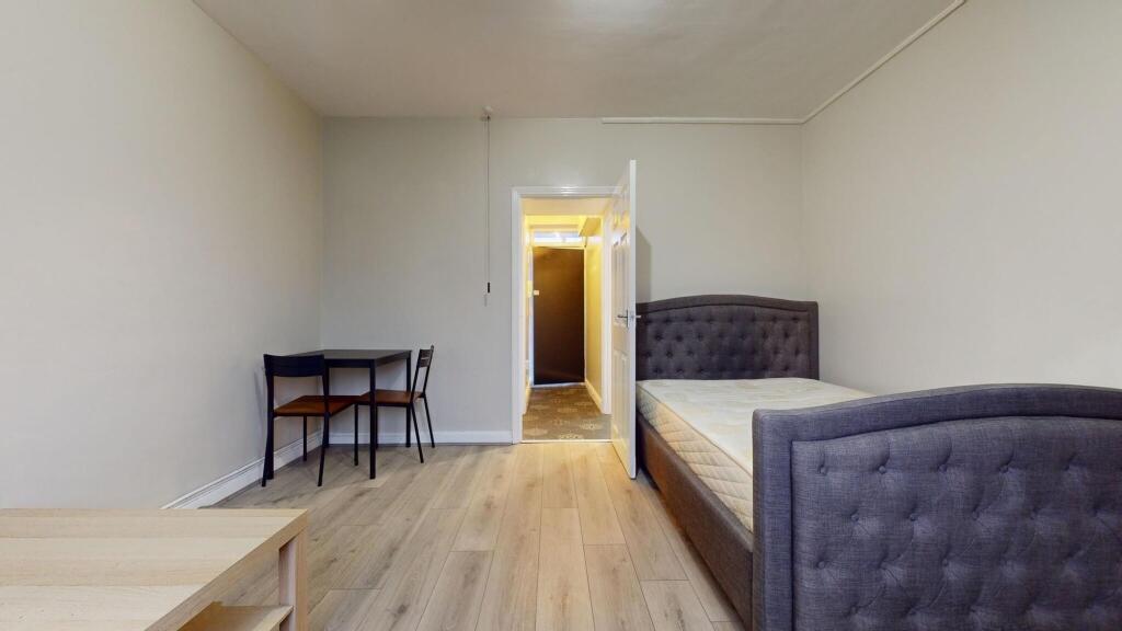 A neat and inviting single bedroom with a cushi...