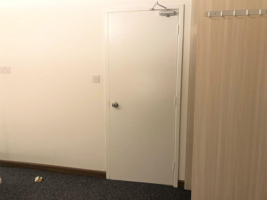 A simple hallway featuring a plain white door a...