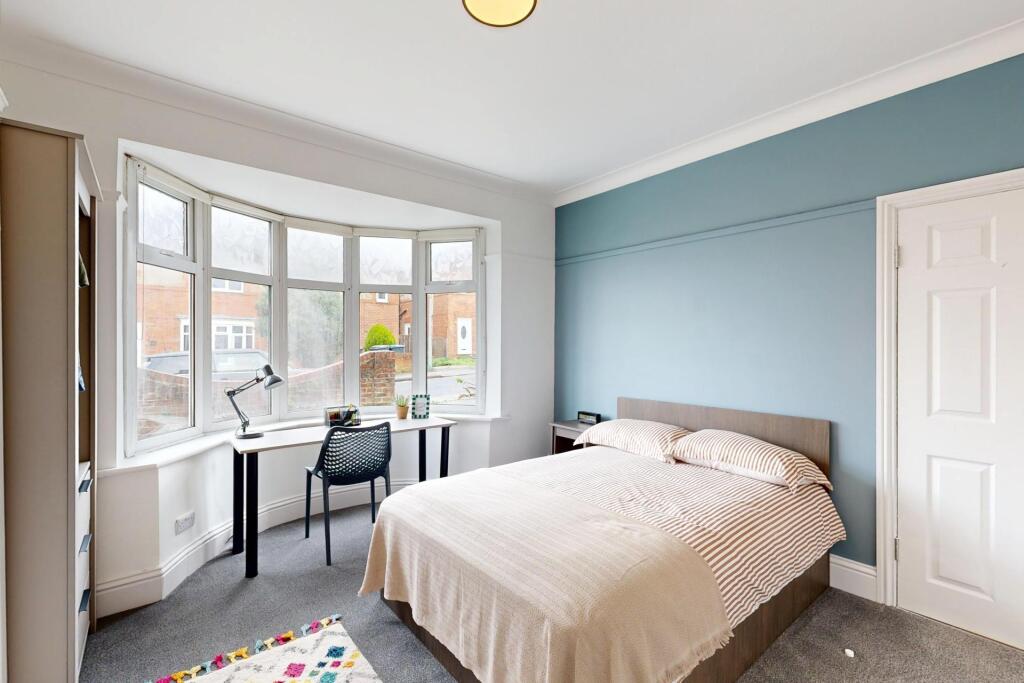 A bright and welcoming bedroom featuring a larg...