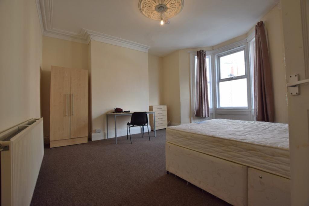 A spacious and well-lit double bedroom with amp...