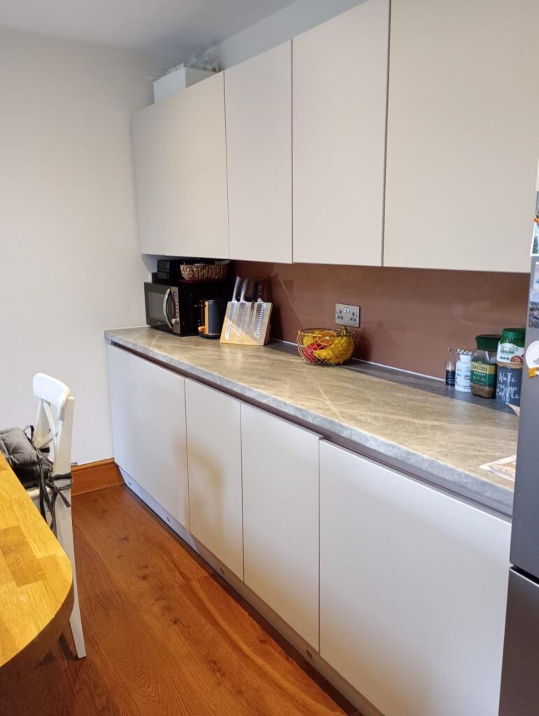 A modern kitchen with white cabinetry and a pol...