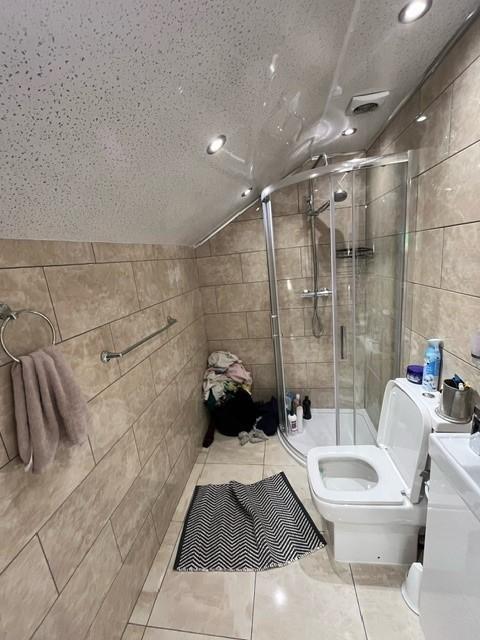 Tiled bathroom with a corner glass shower enclo...