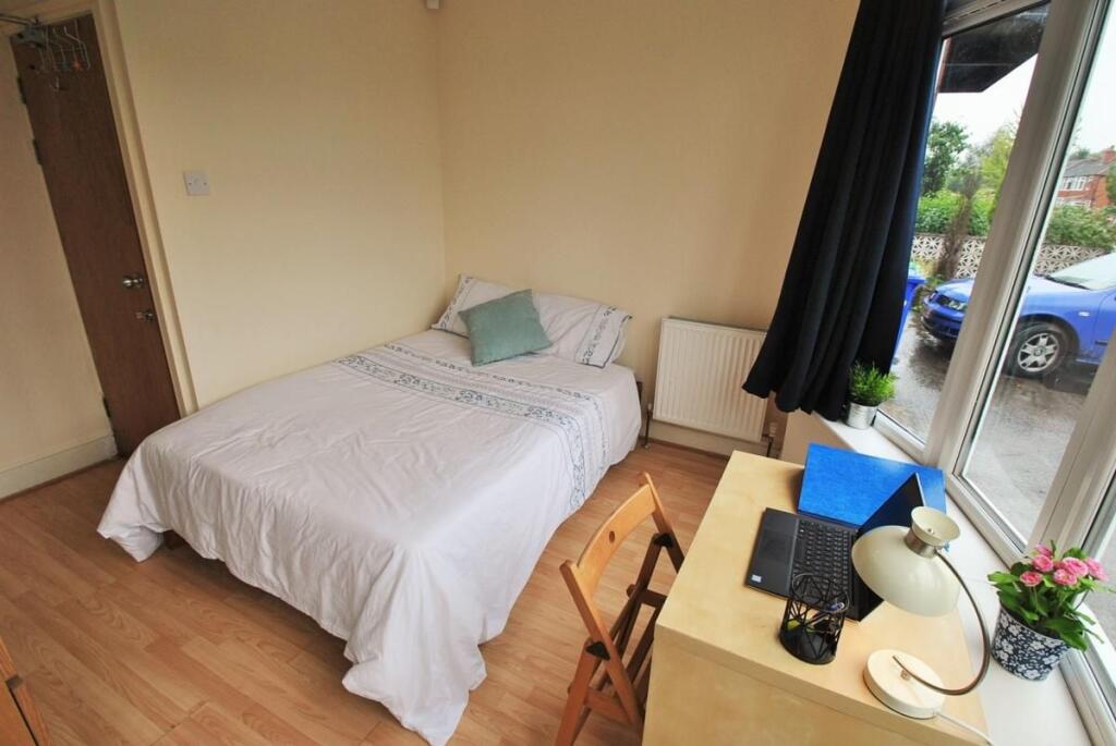 A tidy and well-lit single bedroom featuring a ...