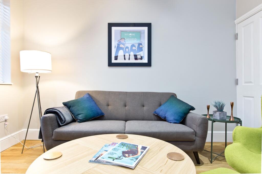 A bright and tidy living room featuring a comfo...