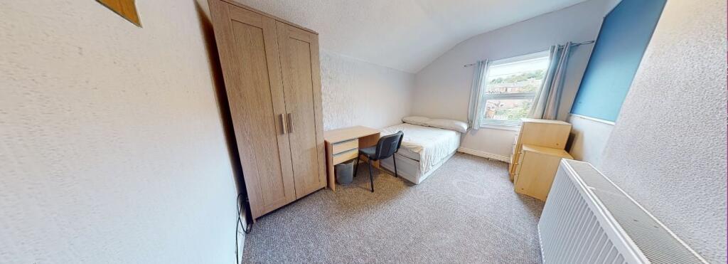 A cozy single bedroom featuring a compact bed, ...