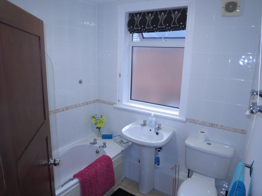 Bright and clean bathroom featuring a bathtub, ...