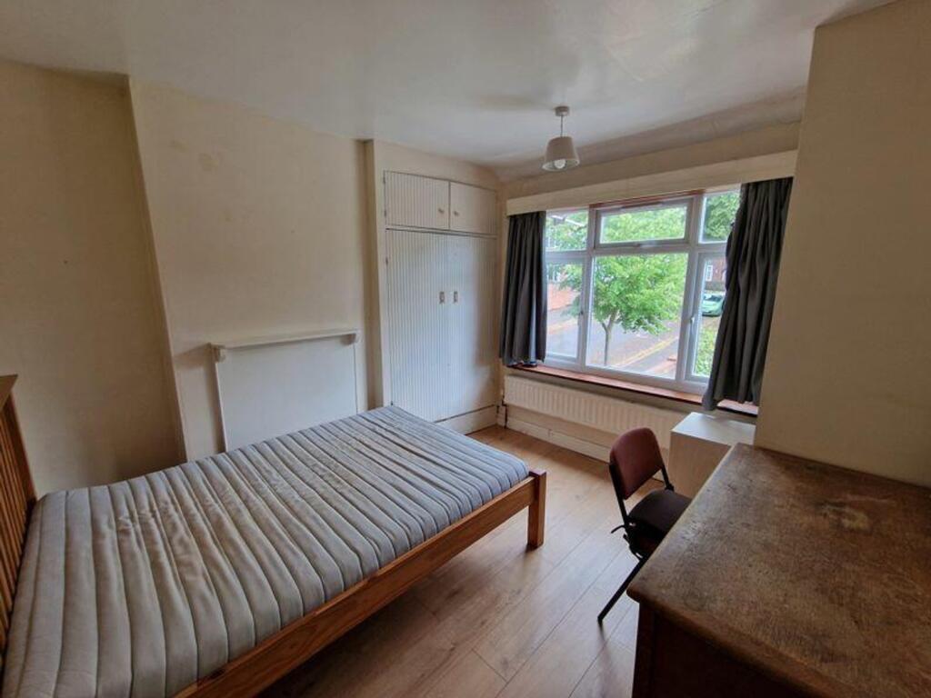 A spacious double bedroom featuring large windo...