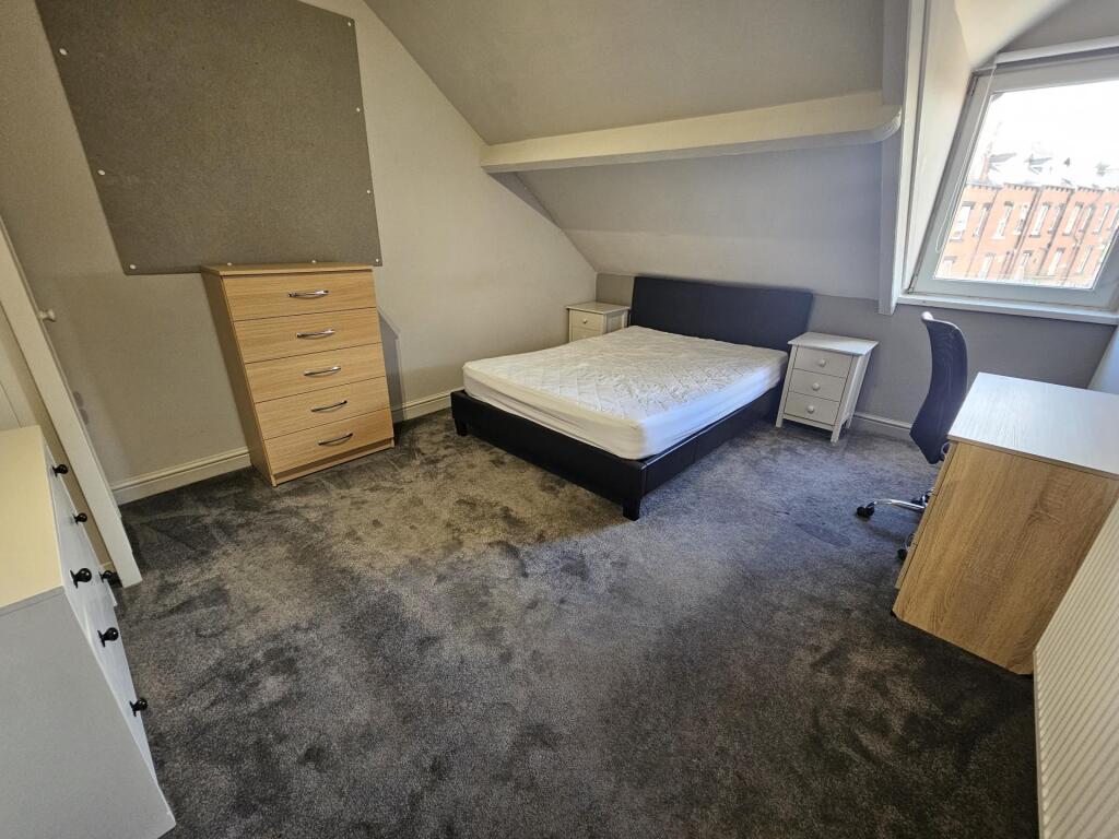 A well-lit bedroom featuring a comfortable doub...