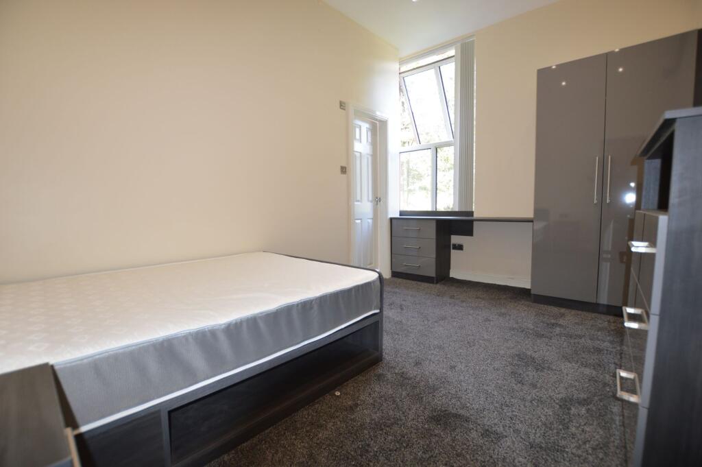 A spacious, well-lit bedroom featuring a large ...