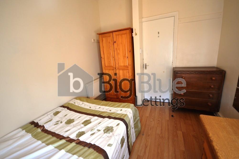 A cozy single bedroom featuring wooden flooring...