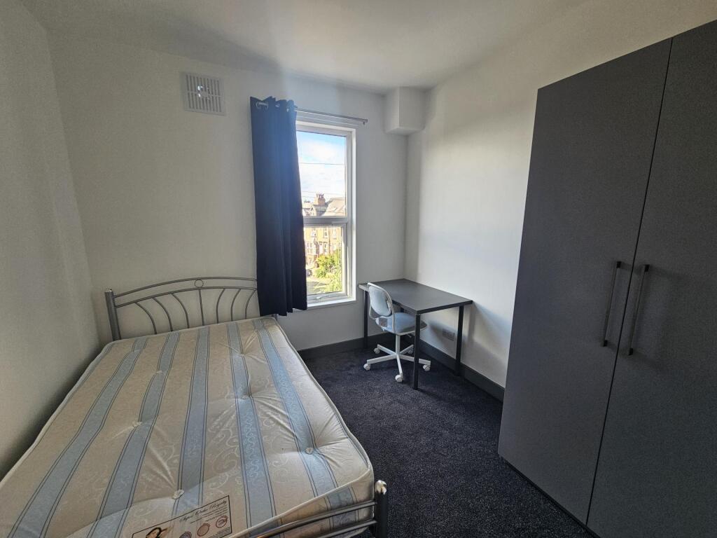 A neat and well-lit single bedroom featuring a ...