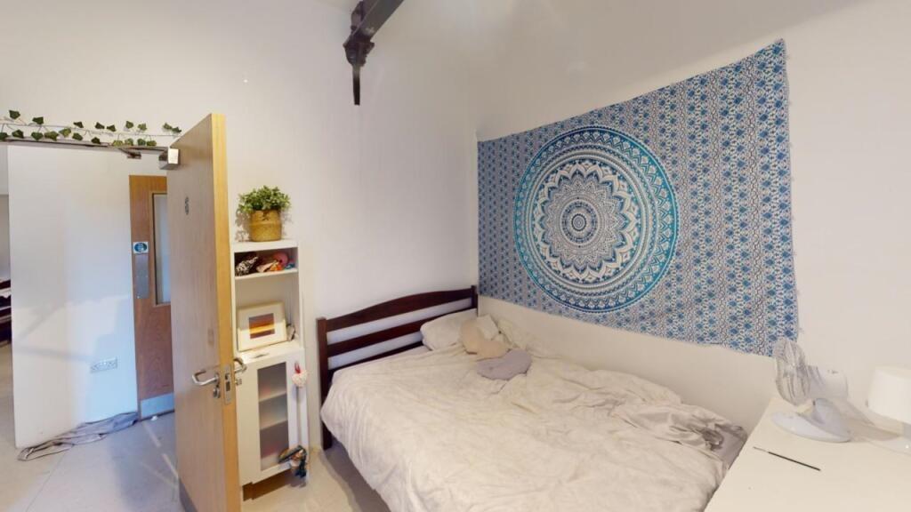 A cozy single bedroom featuring a neat bed with...