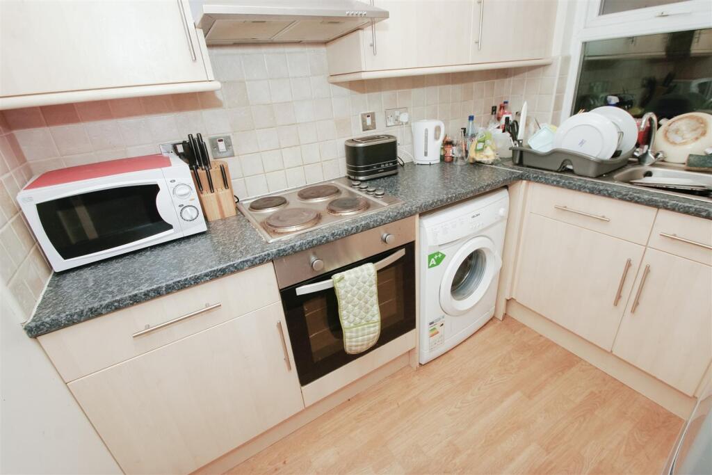 A compact kitchen featuring light wood cabinets...