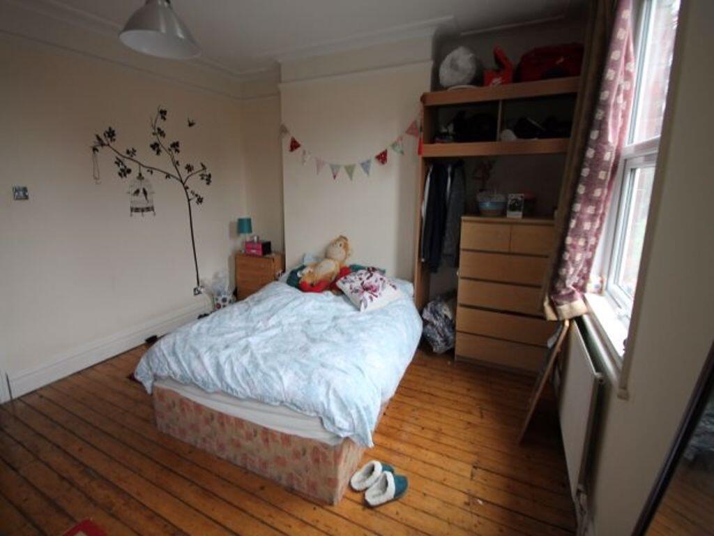 A cozy double bedroom featuring wooden flooring...