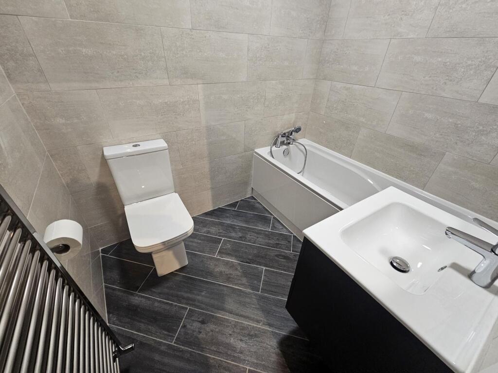 A modern bathroom suite featuring a bathtub, to...